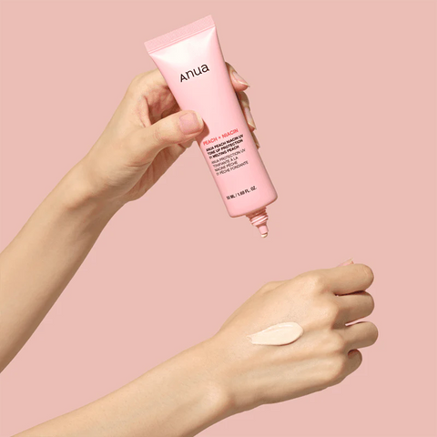 Hand holding a pink Anua product with a swatch on a pink background