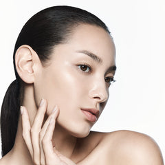 Woman with smooth skin touching her face against a white background