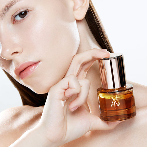 Woman holding a bottle of skincare product with a visible brand logo.