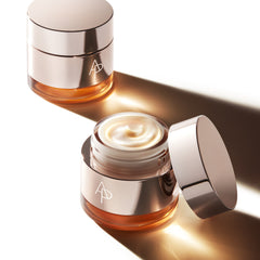 Two skincare jars with cream, one open showing the product, on a white background.
