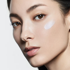 Close-up of a woman's face with a white patch on her cheek against a neutral background