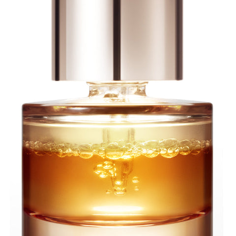 Skincare serum bottle with gold liquid and silver cap on a white background