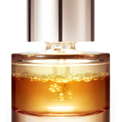 Skincare serum bottle with gold liquid and silver cap on a white background