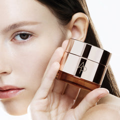 Close-up of a hand holding a skincare product near a person's face