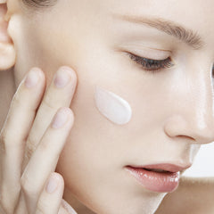 Close-up of a woman applying cream to her face