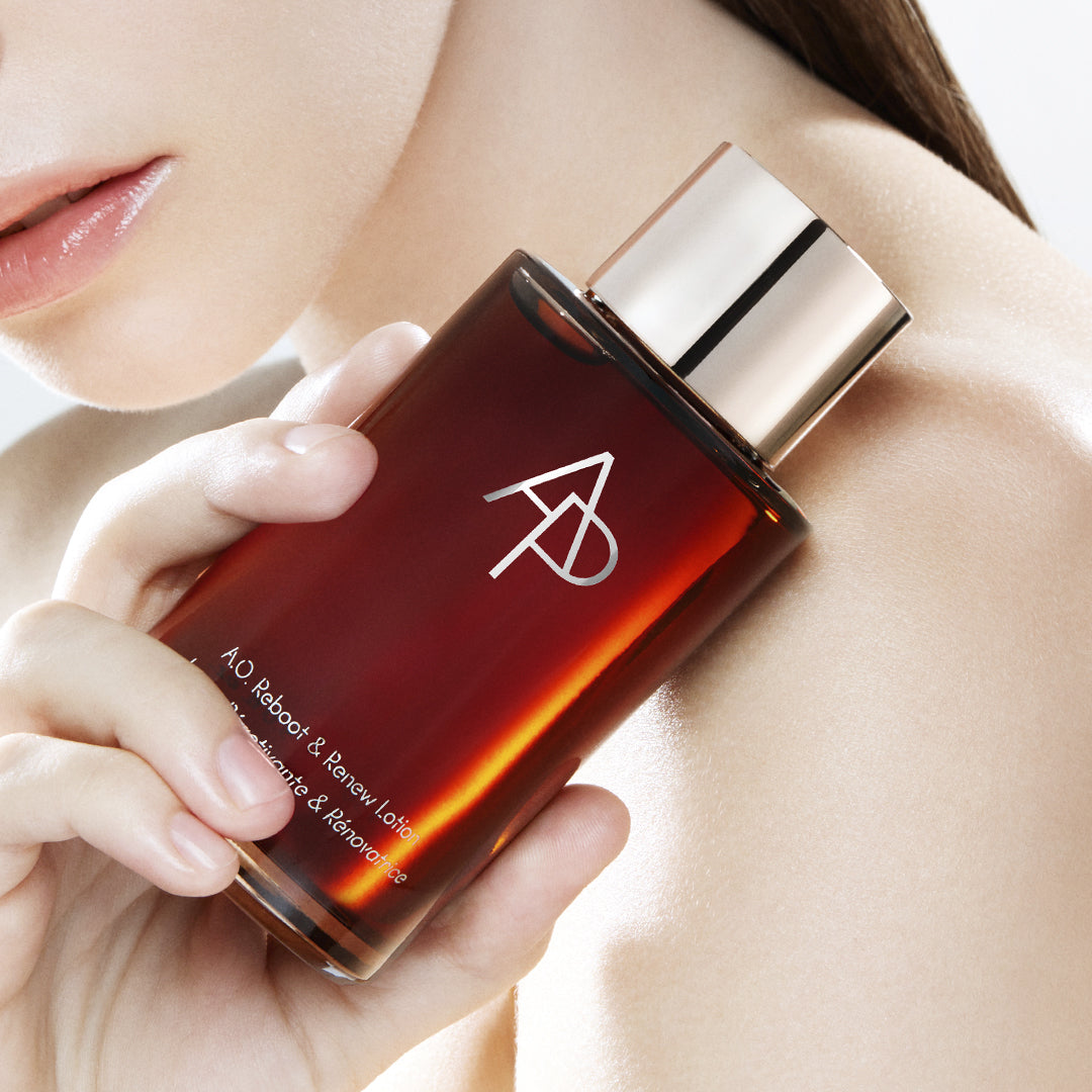 Perfume bottle with a logo held by a person, close-up shot.