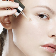 Person applying a dropper of liquid to their face