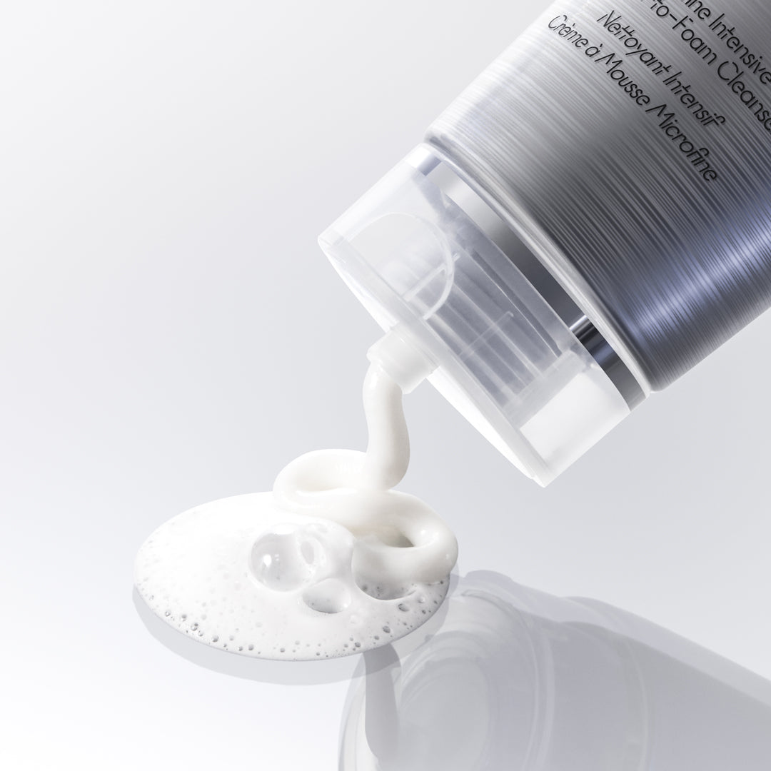 Cosmetic bottle with white foam being poured onto a white surface