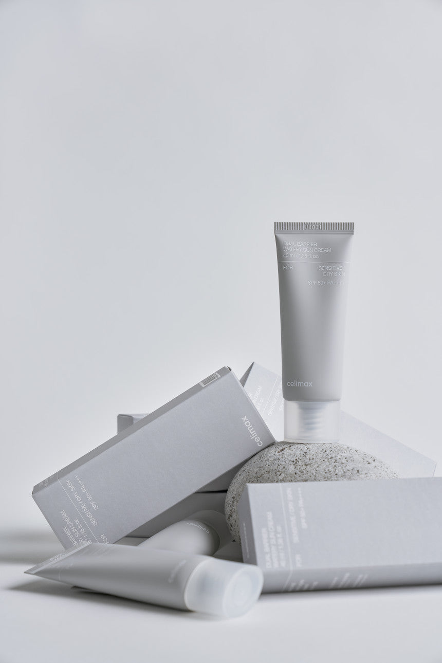 Skincare products including a tube and packets on a light gray background
