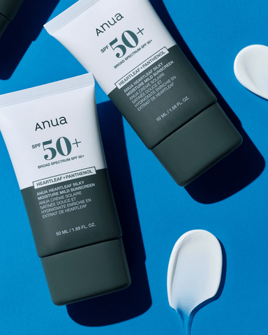 Two Anua sunscreen bottles with SPF 50+ on a blue background