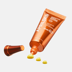 Orange skincare product tube with droplets on a white background