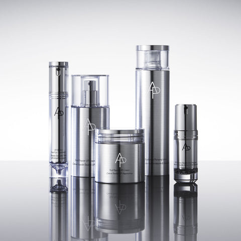 Set of silver skincare products with a logo on a reflective surface
