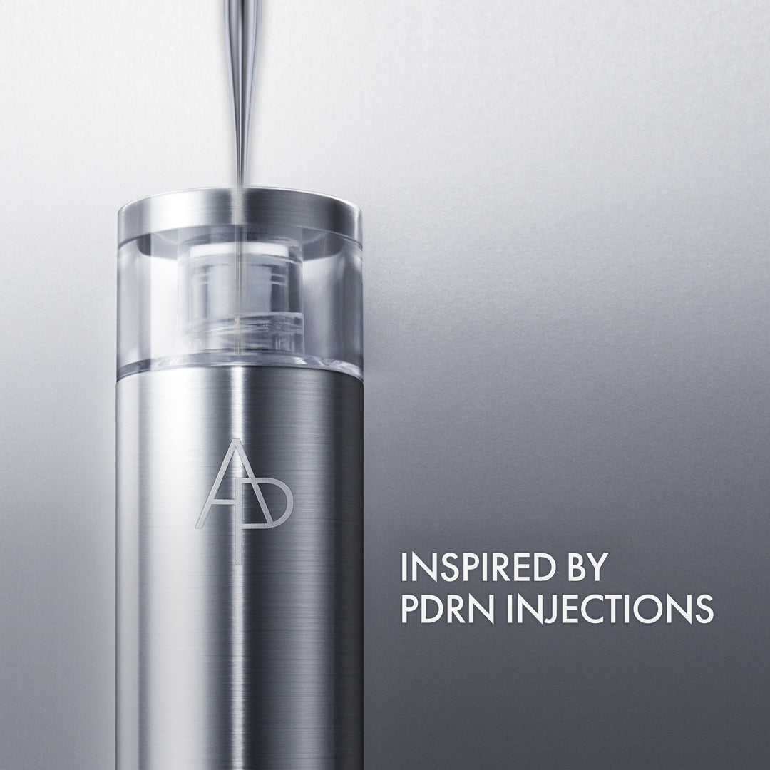 Silver skincare serum bottle with 'AD' logo on a gray background