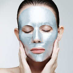 Woman wearing a silver face mask against a plain background