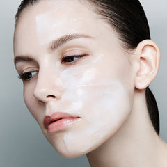 Close-up of a woman's face with a neutral expression on a gray background