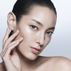 Close-up of a person touching their face against a plain background