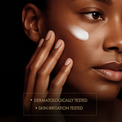 Close-up of a person applying cream to their face with a dark background
