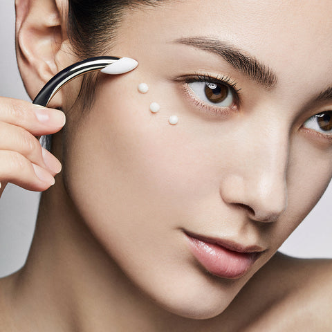 Woman applying cream to her face with a small applicator