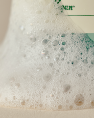 Close-up of a bottle cap with foam and bubbles, featuring the brand 'Cano'.
