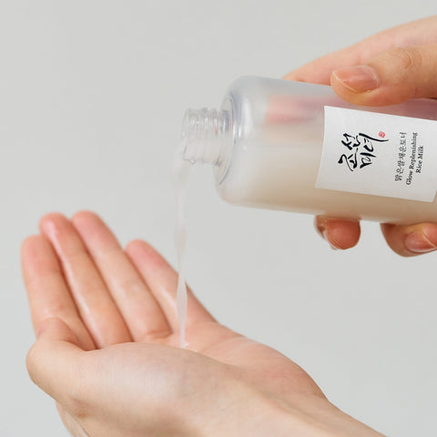 Hand holding a small container of rice milk with a white label against a light gray background