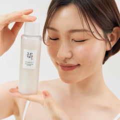 Woman holding a skincare product with a plain background