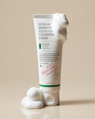 Tube of Sunday Morning Refresh Cleansing Foam with foam on top on a beige background