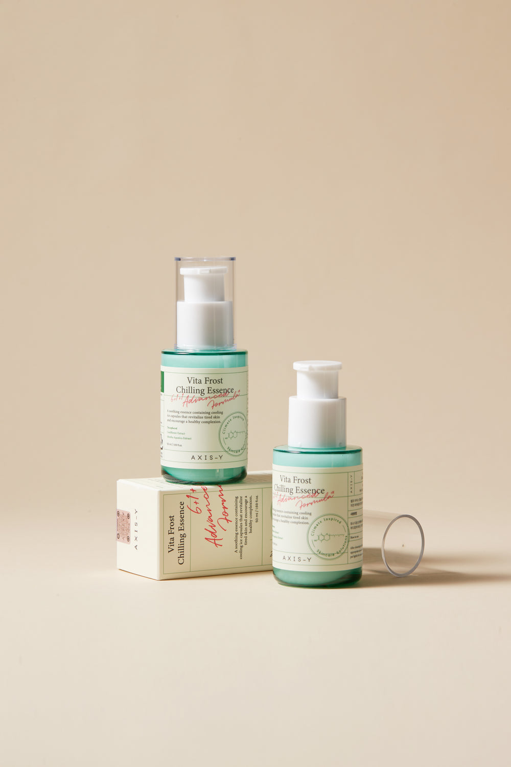 Two skincare bottles with a box on a beige background