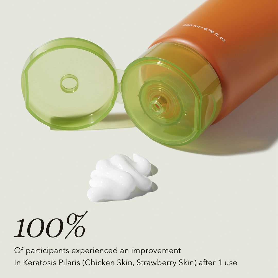 Orange bottle with green cap and white cream on a light background