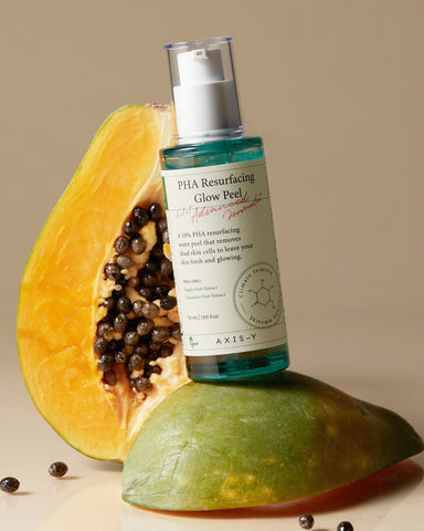 Bottle of 'PHA Resurfacing Glow Peel' by AXIS-V on a halved papaya with seeds.