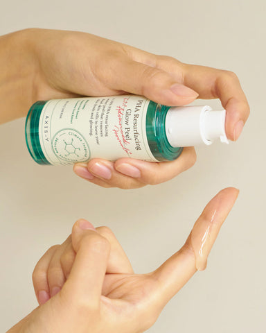 Hand holding a skincare product with a plain background