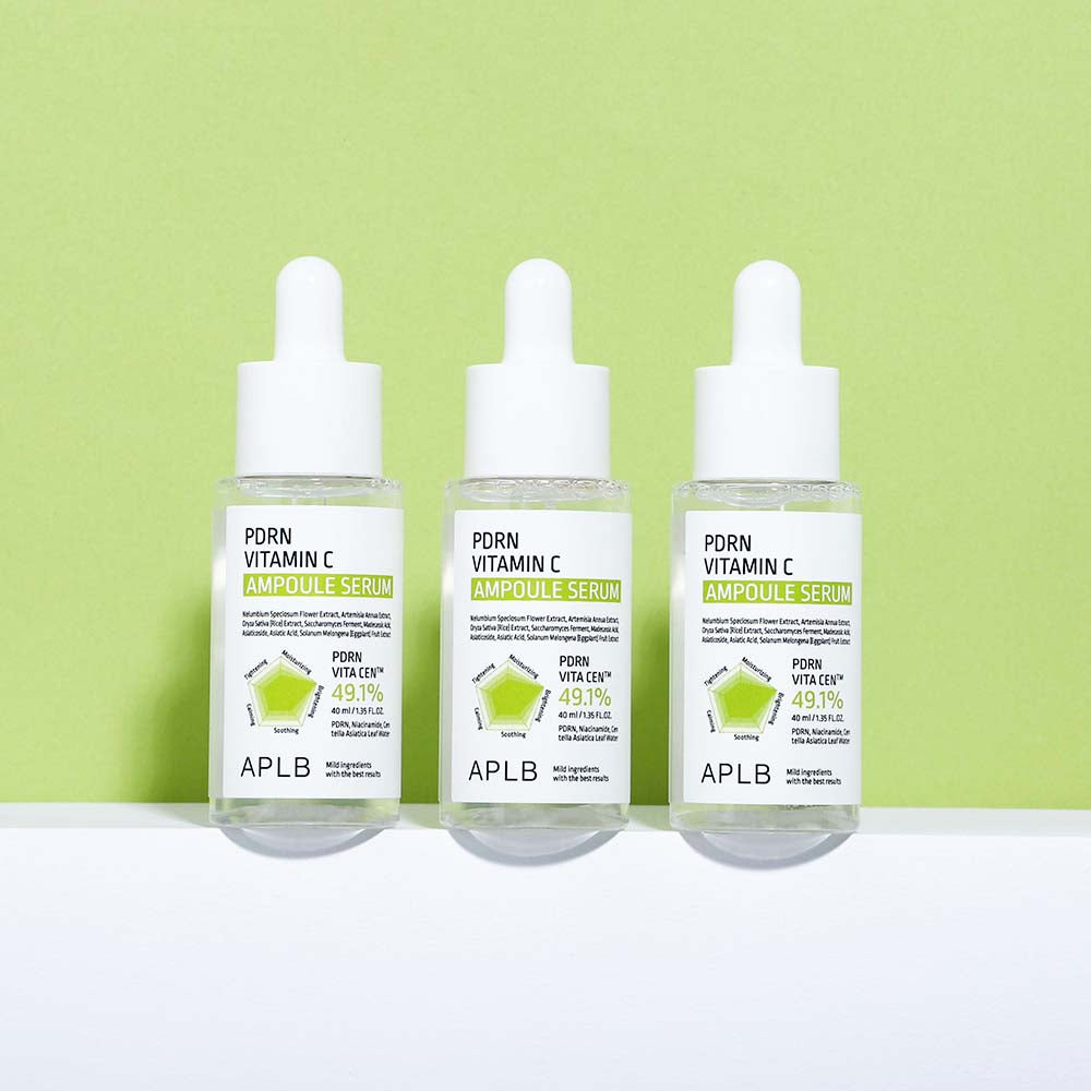 Three bottles of APLB Porn Vitamin C Ampoule Serum on a white surface with a green background