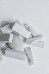 Collection of skincare products including boxes, tubes, and a round product on a light gray background