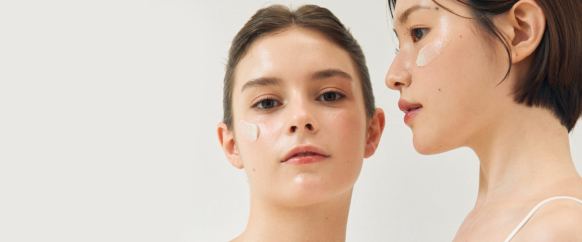 Two women side by side, one with a clear skin patch over her cheek, on a white background.