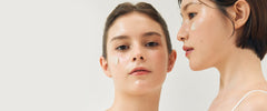 Two women side by side, one with a clear skin patch over her cheek, on a white background.