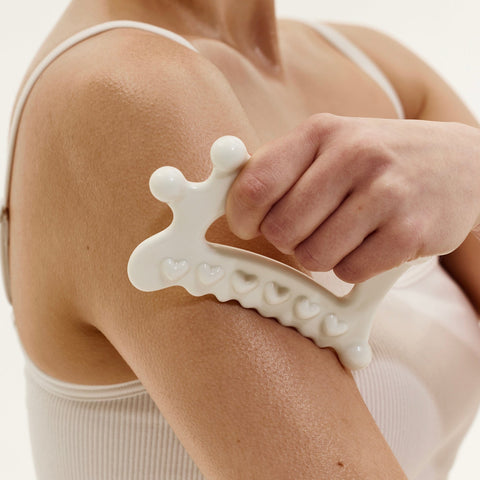 Person using a white textured roller on their arm against a neutral background