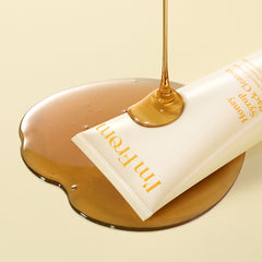 Tube of cream with honey being dripped onto it on a beige background