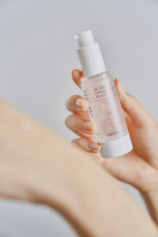 Hand holding a skincare bottle labeled 'celimia' against a neutral background