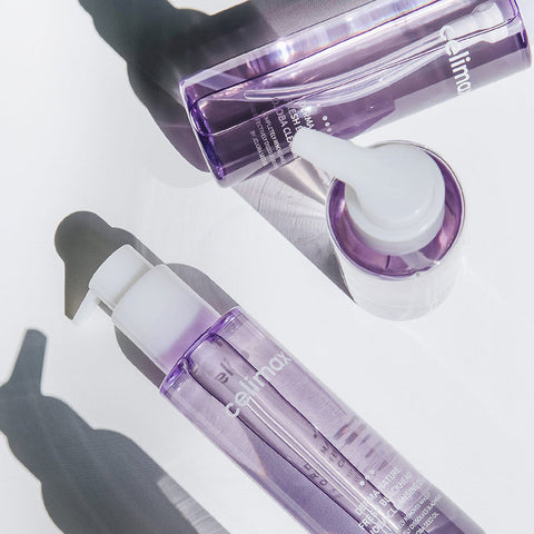 Two purple skincare bottles with droppers on a light background