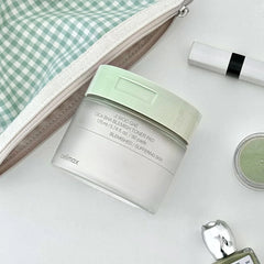 Cosmetic product with green lid and white container on a light surface